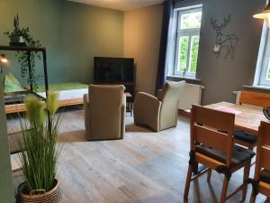 un soggiorno con tavolo e sedie e una sala da pranzo di Apartments und Bistro Zum Glasmacher a Gehlberg
