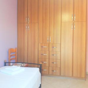 1 dormitorio con 1 cama y un gran armario de madera en OliveTree House, en Vathí - Ítaca