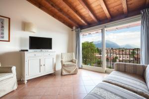 a living room with a couch and a tv and a balcony at Residence Villa Antica Torre in San Felice del Benaco