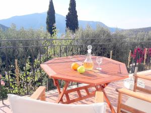 a wooden table with fruit and a bottle on a balcony at OliveTree House in Vathi