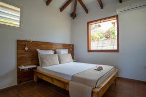 a bedroom with a bed with a wooden headboard and a window at KALYPSO - Les Villas KIKKO in Saint-François