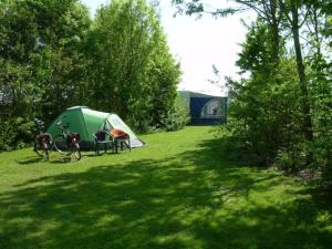 a tent and chairs in a field with trees at 4 persoons ingerichte tent op kleine camping in Anna Paulowna