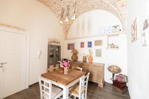 a dining room with a wooden table and a white wall at Camere Caroseno in Castellana Grotte