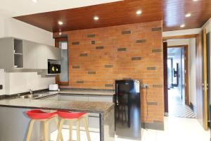 a kitchen with two bar stools and a brick wall at Apt# ONE-FOUR-TWO - with Lift - High Speed Wifi - Smart TV in New Delhi