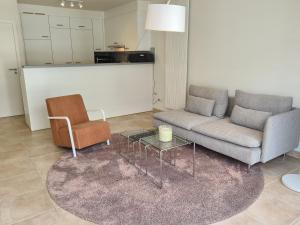 - un salon avec un canapé et une chaise dans l'établissement Oostduinkerke Apartments, à Oostduinkerke