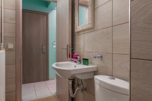y baño con lavabo, aseo y espejo. en Ouzas luxury Hotel en Olympiakí Aktí