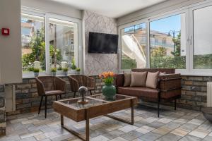 a living room with a couch and chairs and windows at Ouzas luxury Hotel in Olympiaki Akti