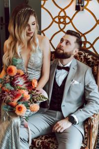 Una sposa e uno sposo seduti su una sedia con un bouquet di Amber Suite Szczecin hotel na Starym Mieście Adults Only a Stettino