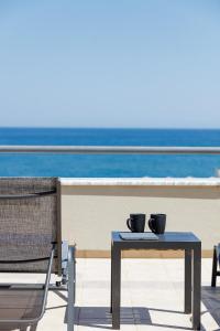 a table with two cups on top of a balcony with the ocean at Adele Riva in Adelianos Kampos