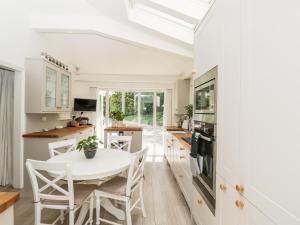 a white kitchen with a white table and chairs at The River House Avon Valley Stonehenge with fishing in Salisbury