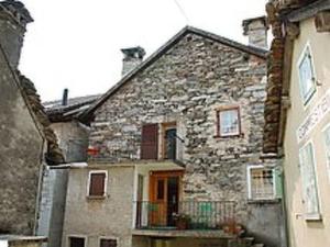 an old stone house with a balcony in a street at Apartment Peppa by Interhome in Chironico