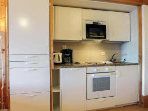 cocina pequeña con armarios blancos y fogones en Apartment Le Bristol B52 by Interhome en Villars-sur-Ollon