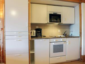 a small kitchen with white cabinets and a stove at Apartment Le Bristol B52 by Interhome in Villars-sur-Ollon