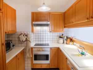 eine kleine Küche mit Holzschränken und einem Waschbecken in der Unterkunft Apartment Le Miclivier B2 by Interhome in Villars-sur-Ollon