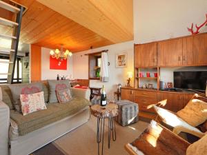 a living room with a couch and a tv and a table at Apartment Les Petites Maraîches 132-389 by Interhome in Taveyannaz