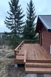 a large wooden deck next to a red building at Holiday Home Korvenniemi by Interhome in Töfsala
