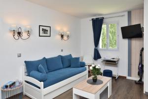 uma sala de estar com um sofá azul e uma mesa em TRES BEL APPARTEMENT 8 PERSONNES WIFI OFFERT em Deauville