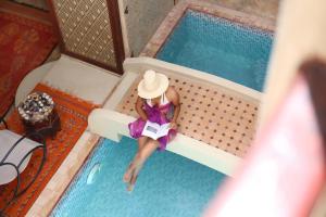 a woman in a hat sitting in a swimming pool at Riad Sidi Mimoune & Spa in Marrakesh