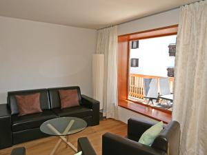 ein Wohnzimmer mit einem schwarzen Sofa und einem Balkon in der Unterkunft Apartment Haus Sonne by Interhome in Erlberg