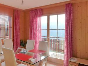 a dining room with a glass table and a large window at Apartment Berg-Seeblick by Interhome in Sundlauenen