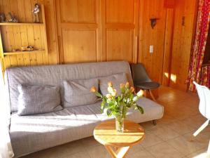 een woonkamer met een bank en een tafel met een vaas met bloemen bij Apartment Centaure A RS 3 by Interhome in Ovronnaz