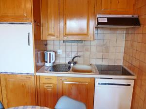 een kleine keuken met houten kasten en een spoelbak bij Apartment Centaure A RS 3 by Interhome in Ovronnaz