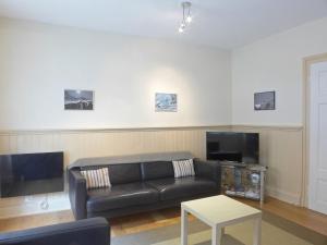 a living room with a black couch and a tv at Apartment Haus Gertsch Apt-G by Interhome in Wengen