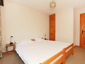 Apartment Zodiaque RS 4 by Interhome في أوفروناز: غرفة نوم بسرير أبيض وخزانة خشبية
