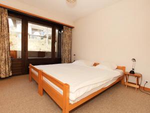 1 dormitorio con cama y ventana grande en Apartment Zodiaque RS 4 by Interhome, en Ovronnaz
