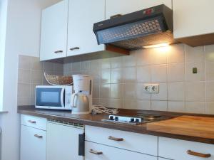 a kitchen with white cabinets and a microwave at Apartment Buchenhöhe-2 by Interhome in Resten