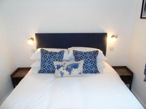 uma cama com almofadas azuis e brancas em Snug - Sealladh Mara Apartment em Helensburgh