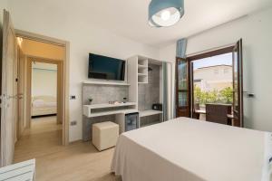 Habitación blanca con cama y TV en Hotel Ristorante La Conchiglia en Cala Gonone