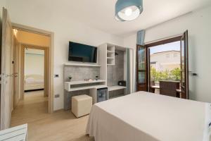 a white room with a bed and a television at Hotel Ristorante La Conchiglia in Cala Gonone