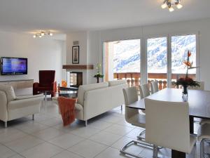 a living room with white furniture and a table and chairs at Apartment Iris A-2 by Interhome in Leukerbad