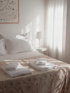 a white bedroom with a bed with towels on it at Casa da Travessa in Ponte de Lima