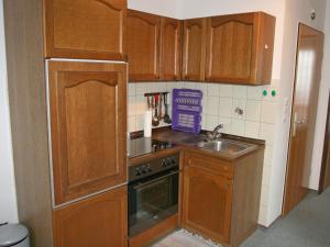 cocina con armarios de madera, fogones y fregadero en Apartment Borkum by Interhome, en Dornumersiel