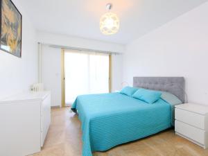 een witte slaapkamer met een blauw bed en een raam bij Apartment Lerins by Interhome in Cannes