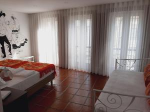 a hotel room with two beds and windows with curtains at Casa da Travessa in Ponte de Lima