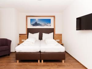 een slaapkamer met een bed met witte kussens bij Apartment Stöcklhof-1 by Interhome in Pettneu am Arlberg