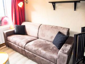 a brown leather couch with two pillows on it at Apartment Villaret 604 by Interhome in Les Menuires