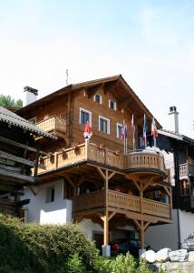 un grand bâtiment en bois avec drapeaux. dans l'établissement B&B Café de la Poste, à Agettes