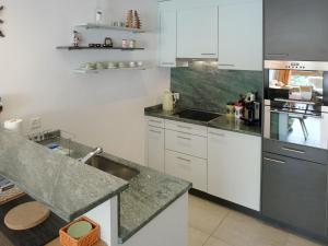 eine Küche mit weißen Schränken und Granitarbeitsflächen in der Unterkunft Apartment Chesa Boffalora by Interhome in Valbella