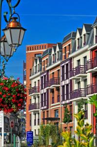una fila de edificios de apartamentos con balcones y luz de la calle en Résidence Goélia Belle Epoque, en Mers-les-Bains