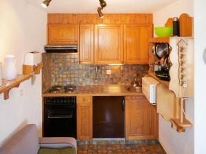 a kitchen with wooden cabinets and a black dishwasher at Apartment Foret E3 by Interhome in Nendaz