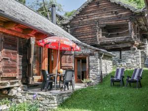 a table with chairs and an umbrella outside of a house at Holiday Home Rustico Cà dru Lurenz by Interhome in Malvaglia