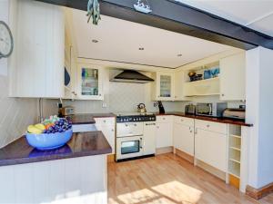 a kitchen with white cabinets and a bowl of fruit on a counter at Holiday Home Albert by Interhome in Fowey