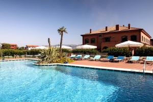 a swimming pool with chairs and umbrellas next to a building at Il Picciolo Etna Golf Resort & Spa in Castiglione di Sicilia