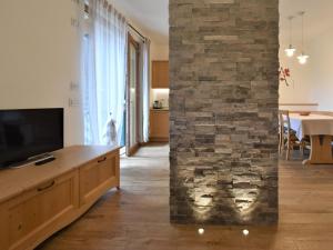 salon z telewizorem i kamienną ścianą w obiekcie Apartment Elettra-7 by Interhome w mieście Crone +26 zdjęć