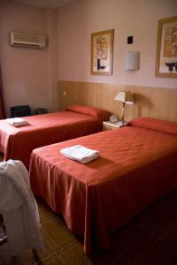 a hotel room with two beds with red sheets at Hotel Las Terrazas in Albolote