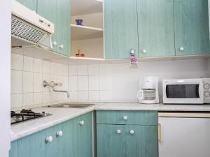 a kitchen with blue cabinets and a microwave at Apartment Cortaderia 2 by Interhome in Balatonkeresztúr